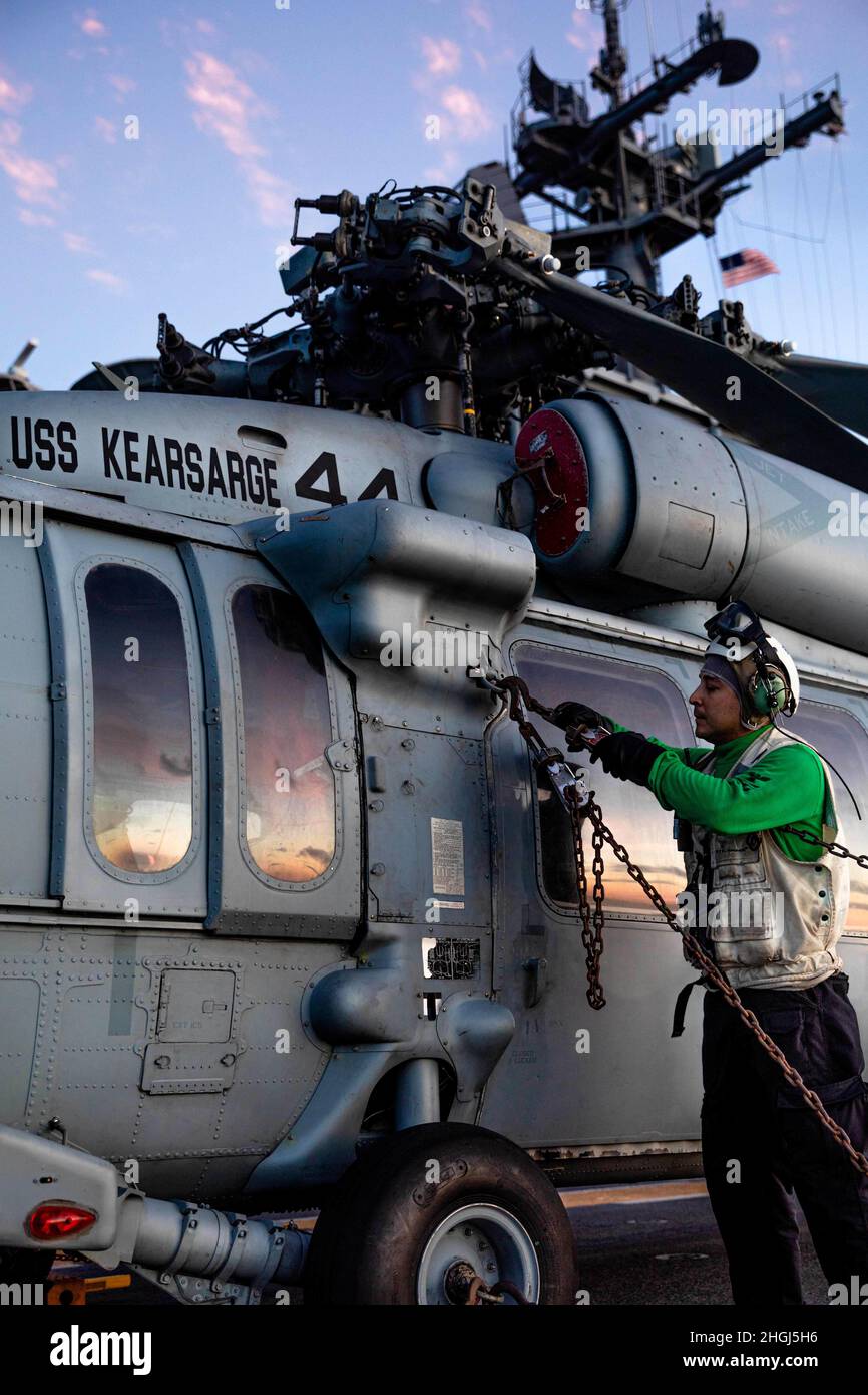 210812-N-IK871-1043 OCEANO ATLANTICO (AGOSTO 12, 2021) meccanica strutturale aeronautica 1a classe Carlos Mercado, assegnato a Helicopter Sea Combat Squadron (HSC) 28, controlla l'integrità delle catene che fissano un elicottero MH-60S Sea Hawk al ponte di volo della nave d'assalto anfibio di classe Wasp USS Kearsarge (LHD 3) 12 agosto 2021. Kearsarge è in corso per supportare Large Scale Exercise (LSE) 2021. LSE 2021 dimostra la capacità della Marina di impiegare una forza precisa, letale e schiacciante a livello globale attraverso tre comandi di componenti navali, cinque flotte numerate e 17 fusi orari. LSE 2021 si fonde dal vivo e. Foto Stock