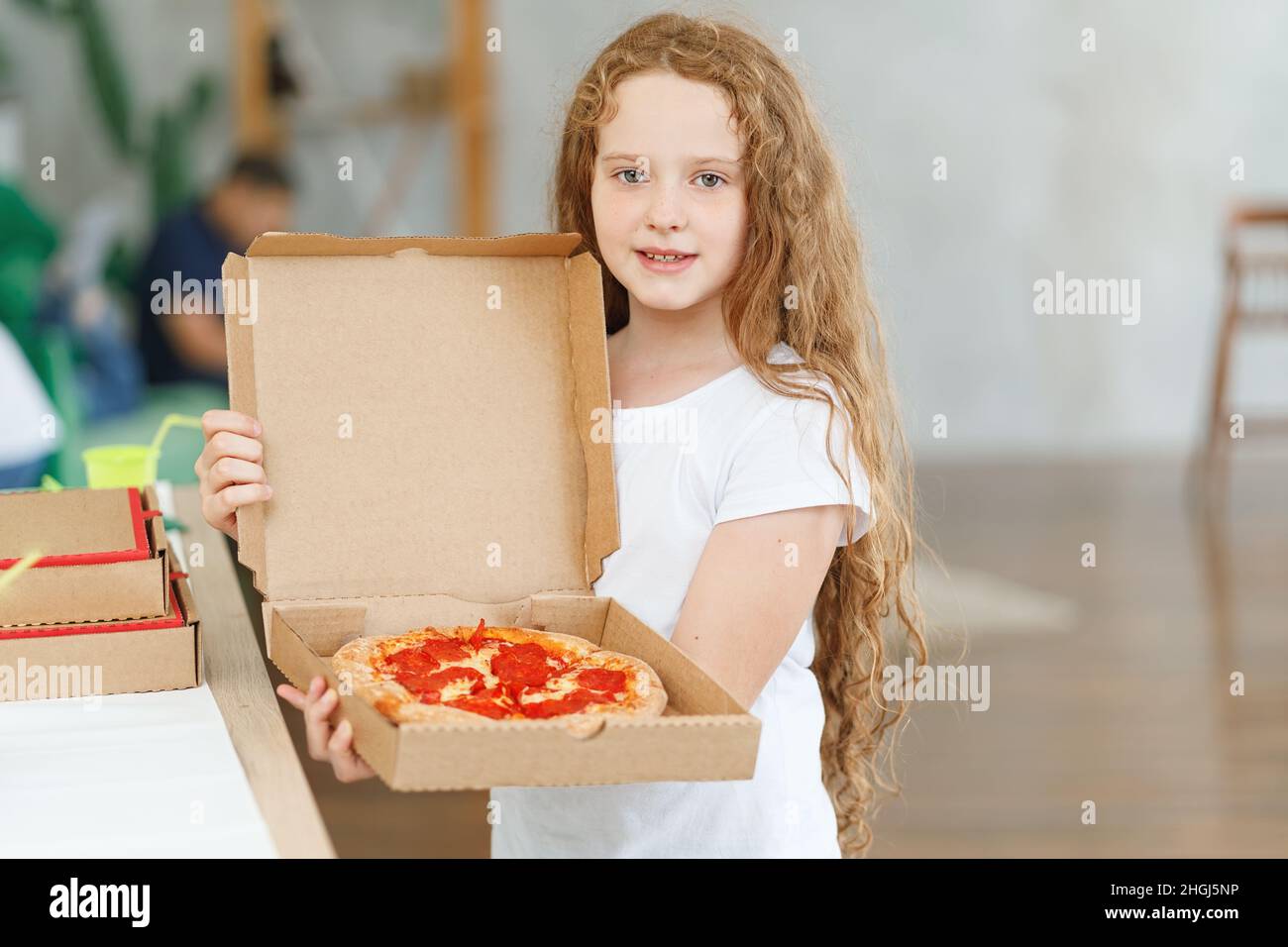 Piccola ragazza felice che tiene la scatola con la pizza di peperoni. Foto Stock