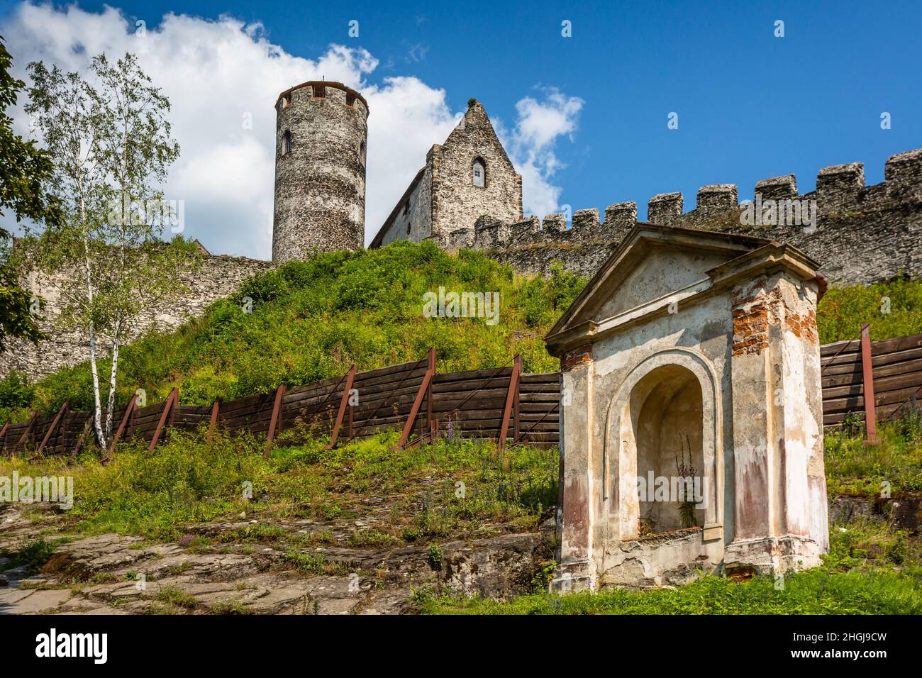 Bezdez, Repubblica Ceca - Luglio 24 2021: Vista della cappella, torre e una casa, parti del castello medievale fatto di pietre grigie in piedi su un verde hil Foto Stock