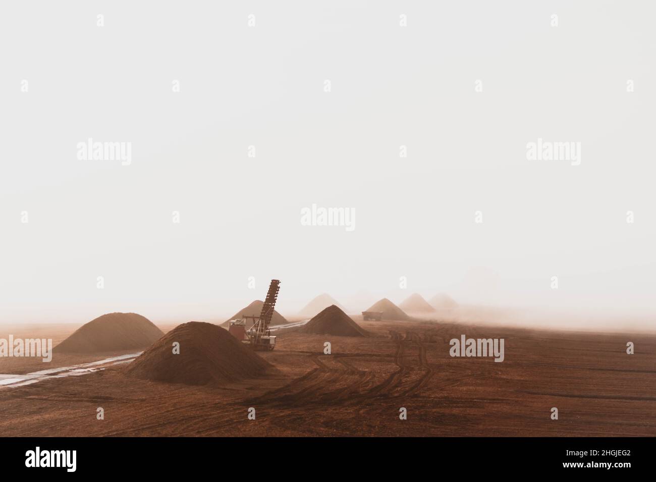 Vista areale di mucchi di torba, escavatore e rimorchio in una mattinata di nebbia. Foto Stock