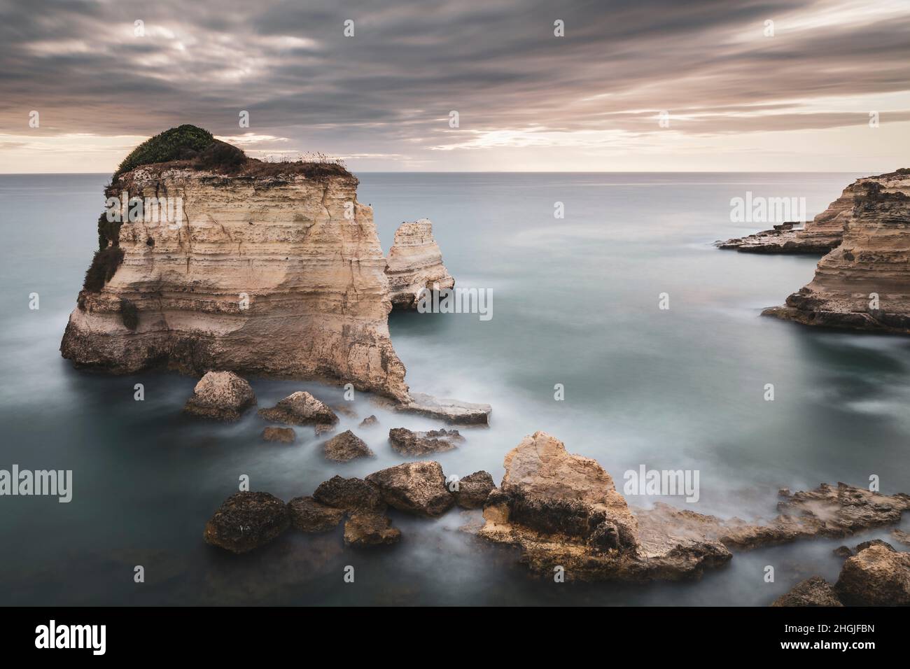 Una lunga esposizione fotografica dell'alba di fronte alle pile di Sant'Andrea, Puglia, Italia Foto Stock