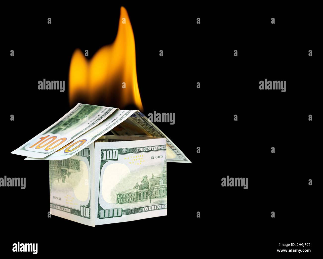 Casa in fiamme fatta da cento dollari bollette isolato su sfondo nero. Concetto creativo di assicurazione di proprietà e fuoco. Foto Stock