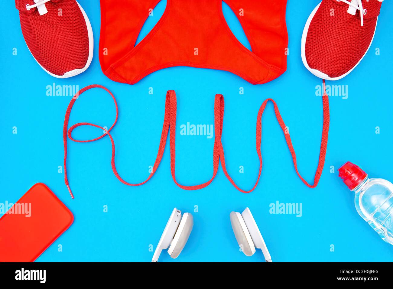 Word RUN a forma di una scarpa incorniciata con abbigliamento da corsa e accessori isolati su blu. Sfondo motivazione stile di vita attivo. Foto Stock
