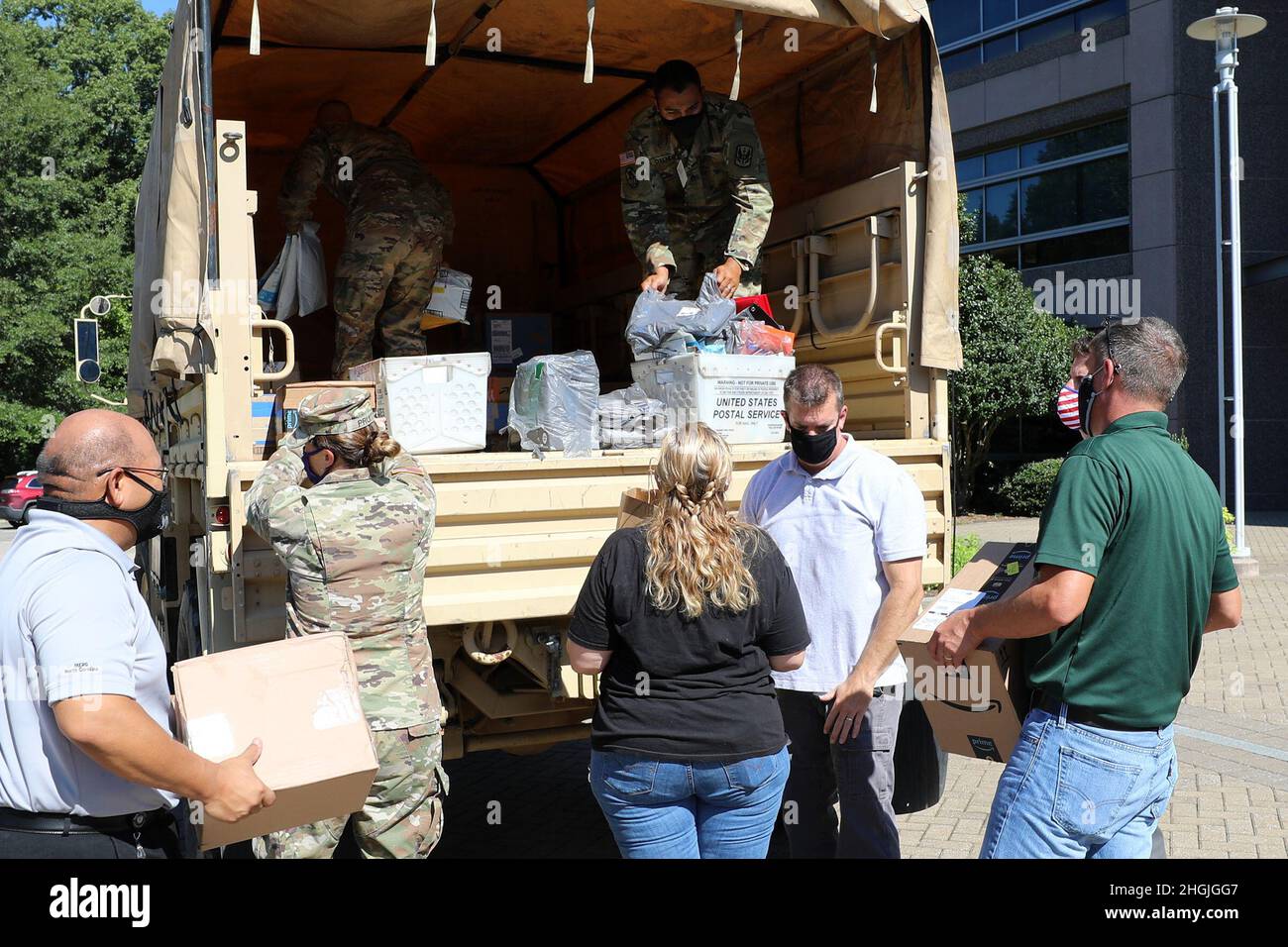 I soldati della Guardia Nazionale del North Carolina aiutano i dipendenti della John Deere Turf and Utility Division a caricare le forniture scolastiche donate come parte dei programmi familiari della Guardia Nazionale del North Carolina del 2021 a Cary, North Carolina, 19 agosto 2021. I membri del gruppo di apprezzamento militare dell'azienda, North Carolina Military Employee Resource Group, si sono Uniti ai soldati NCNG per caricare le forniture in un veicolo tattico medio leggero per il trasporto dagli uffici dell'azienda a Cary alla sede centrale di NCNG a Raleigh, North Carolina, per la successiva distribuzione alle famiglie della Guardia a livello statale. Foto Stock