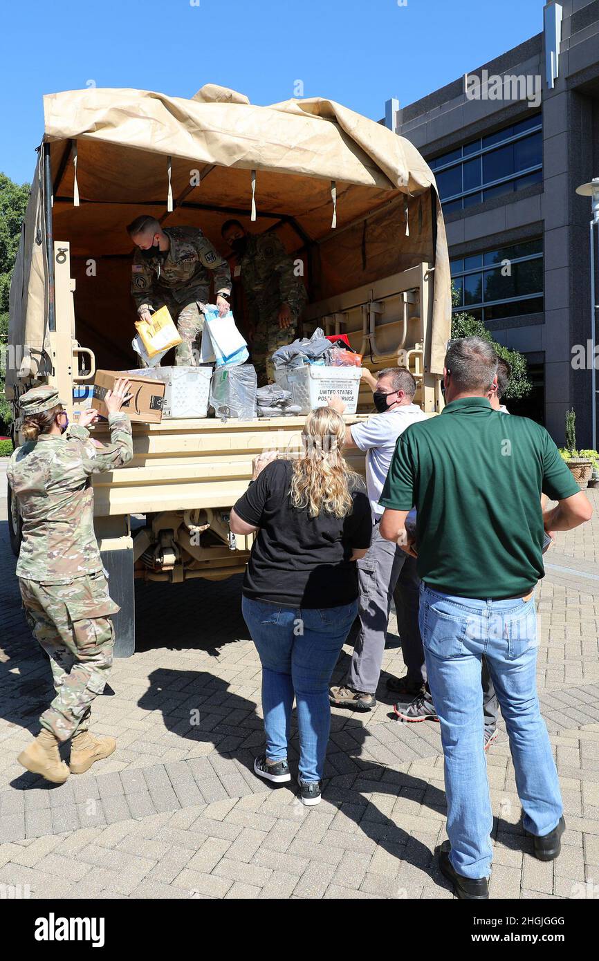 I soldati della Guardia Nazionale del North Carolina aiutano i dipendenti della John Deere Turf and Utility Division a caricare le forniture scolastiche donate come parte dei programmi familiari della Guardia Nazionale del North Carolina del 2021 a Cary, North Carolina, 19 agosto 2021. I membri del gruppo di apprezzamento militare dell'azienda, North Carolina Military Employee Resource Group, si sono Uniti ai soldati NCNG per caricare le forniture in un veicolo tattico medio leggero per il trasporto dagli uffici dell'azienda a Cary alla sede centrale di NCNG a Raleigh, North Carolina, per la successiva distribuzione alle famiglie della Guardia a livello statale. Foto Stock