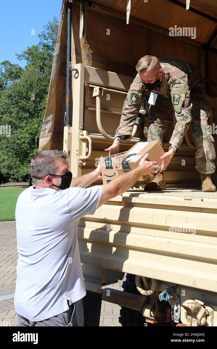 I soldati della Guardia Nazionale del North Carolina aiutano i dipendenti della John Deere Turf and Utility Division a caricare le forniture scolastiche donate come parte dei programmi familiari della Guardia Nazionale del North Carolina del 2021 a Cary, North Carolina, 19 agosto 2021. I membri del gruppo di apprezzamento militare dell'azienda, North Carolina Military Employee Resource Group, si sono Uniti ai soldati NCNG per caricare le forniture in un veicolo tattico medio leggero per il trasporto dagli uffici dell'azienda a Cary alla sede centrale di NCNG a Raleigh, North Carolina, per la successiva distribuzione alle famiglie della Guardia a livello statale. Foto Stock