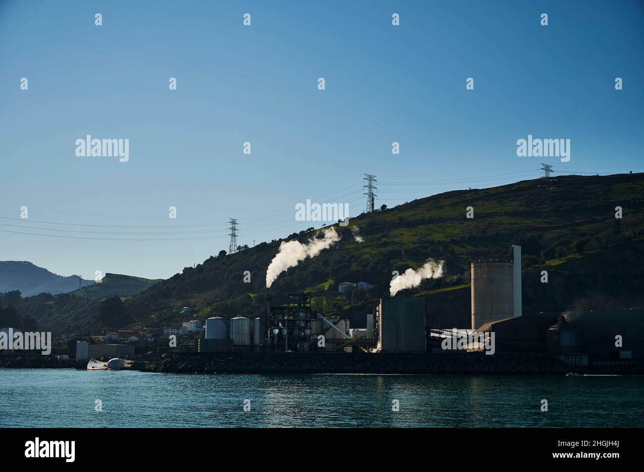 Due camini emettono fumo bianco all'alba sulla riva del mare Foto Stock