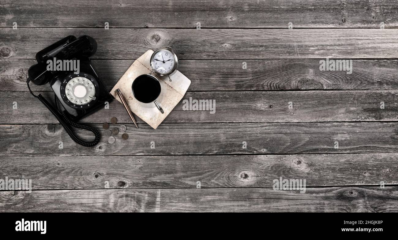 Tavolo da ufficio in legno invecchiato con telefono rotante retrò, caffè, busta, penna, orologio e monete. Vista dall'alto con ampio spazio per la copia in formato a disposizione piatta Foto Stock
