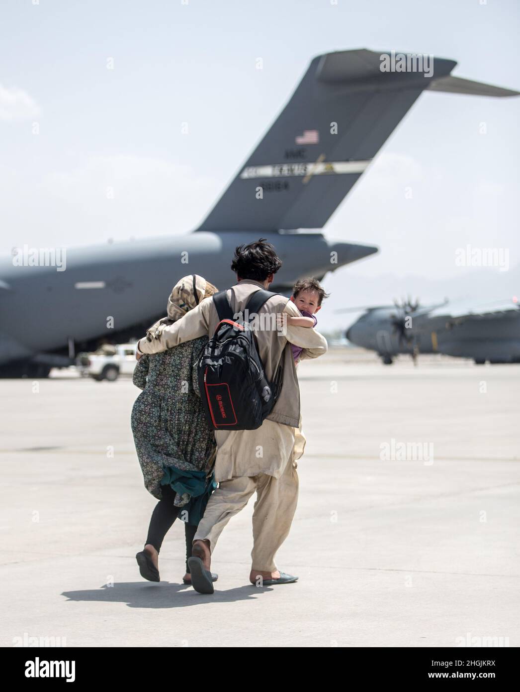 Una famiglia cammina verso un Boeing C-17 Globemaster III dell'aeronautica degli Stati Uniti durante un'evacuazione all'aeroporto internazionale Hamid Karzai, Kabul, Afghanistan, agosto 22. I membri del servizio degli Stati Uniti stanno assistendo il Dipartimento di Stato con un prelievo ordinato di personale designato in Afghanistan. Foto Stock