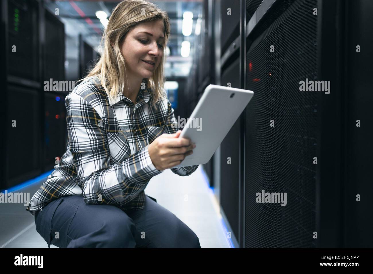 Tecnico del data center femminile che lavora all'interno della sala rack del server Foto Stock