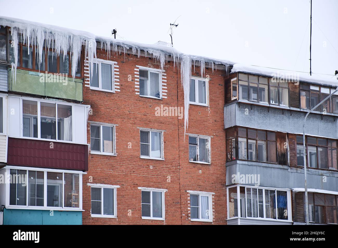 Ghiaccioli giganti appesi giù dal tetto di una vecchia casa residenziale di mattoni. Ghiaccioli pericolosi pende dal tetto. Inverno Nord duro. Foto Stock
