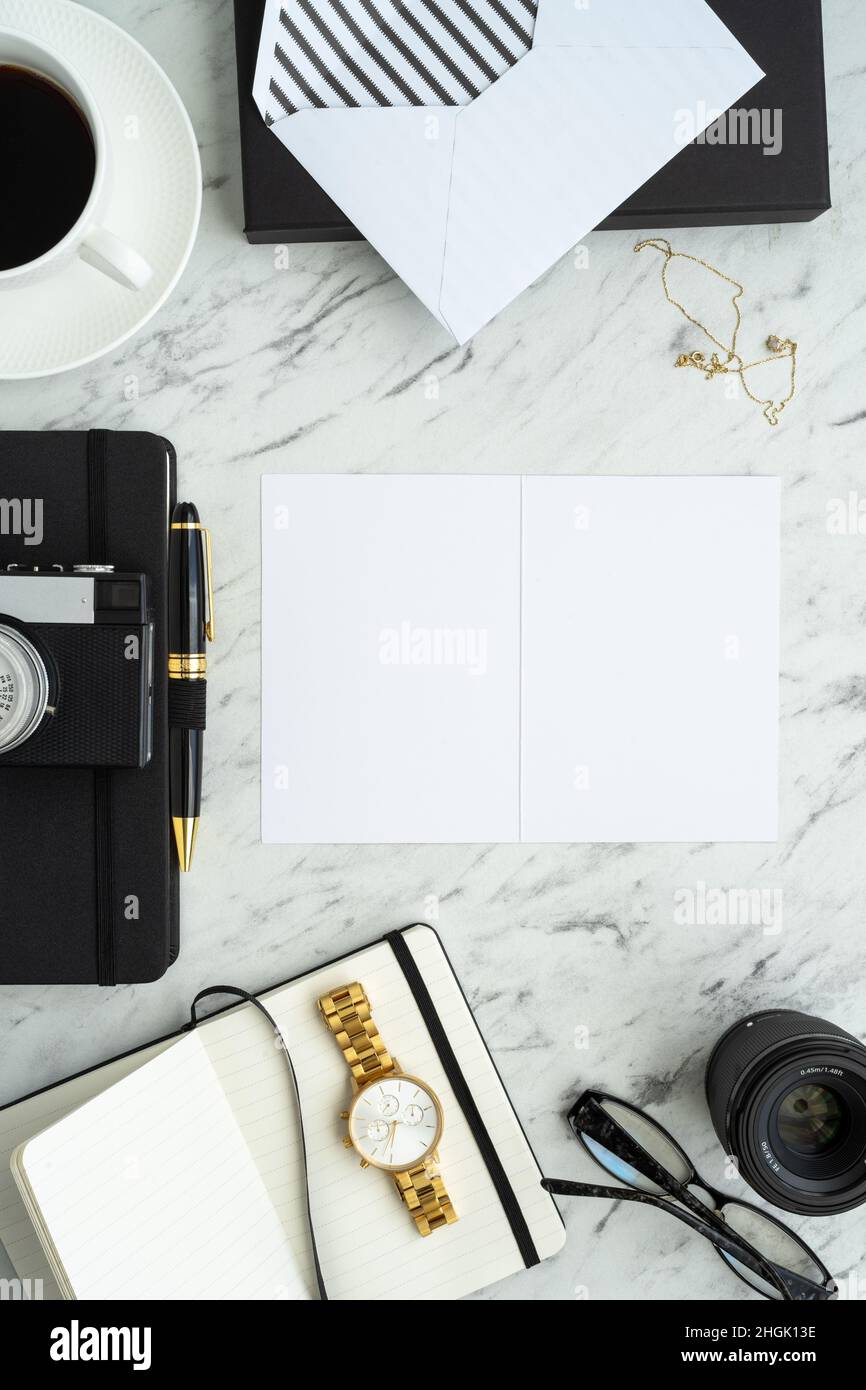 Un elegante blogger o una scrivania per fotografi con una macchina fotografica, una tazza di caffè, un notebook, un orologio da polso, un obiettivo, penna e bicchieri Foto Stock