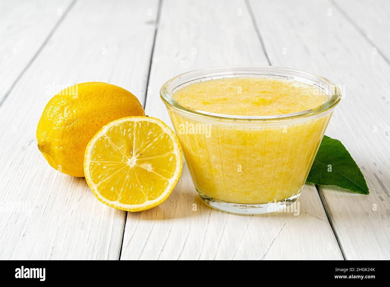 Marmellata di limone freezer in una ciotola di vetro su un vecchio tavolo di legno. Marmellata fresca fatta senza cuoco di agrumi succosi maturi mescolati con lo zucchero. Purea di acido amidacea. Foto Stock