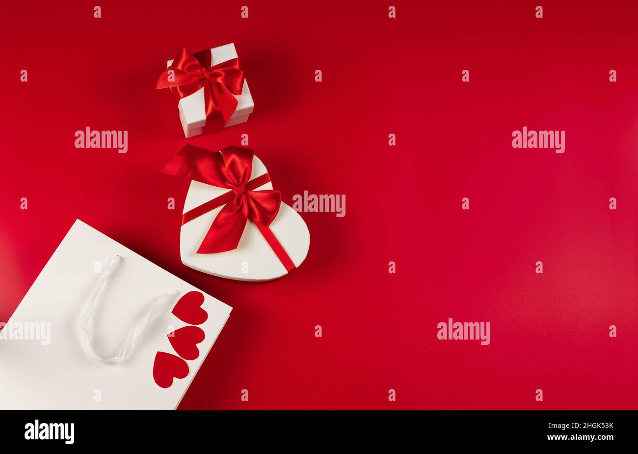 Disposizione piatta. Imballaggio per acquisti, regali e pacchi su sfondo rosso Foto Stock
