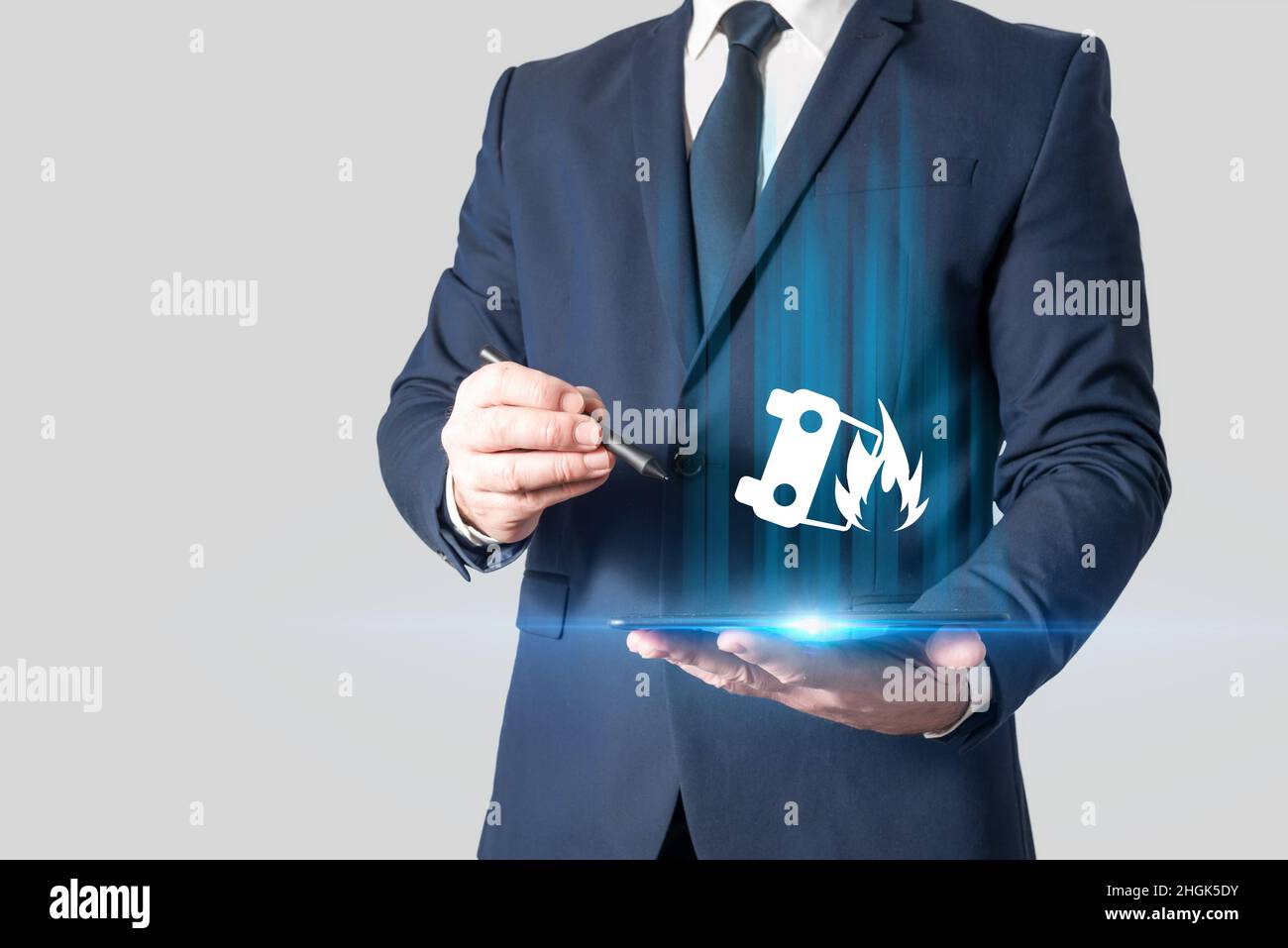 Agente assicurativo che tiene un tablet con un'immagine di un'auto in fiamme. Assicurazione auto. Protezione contro gli incidenti stradali Foto Stock