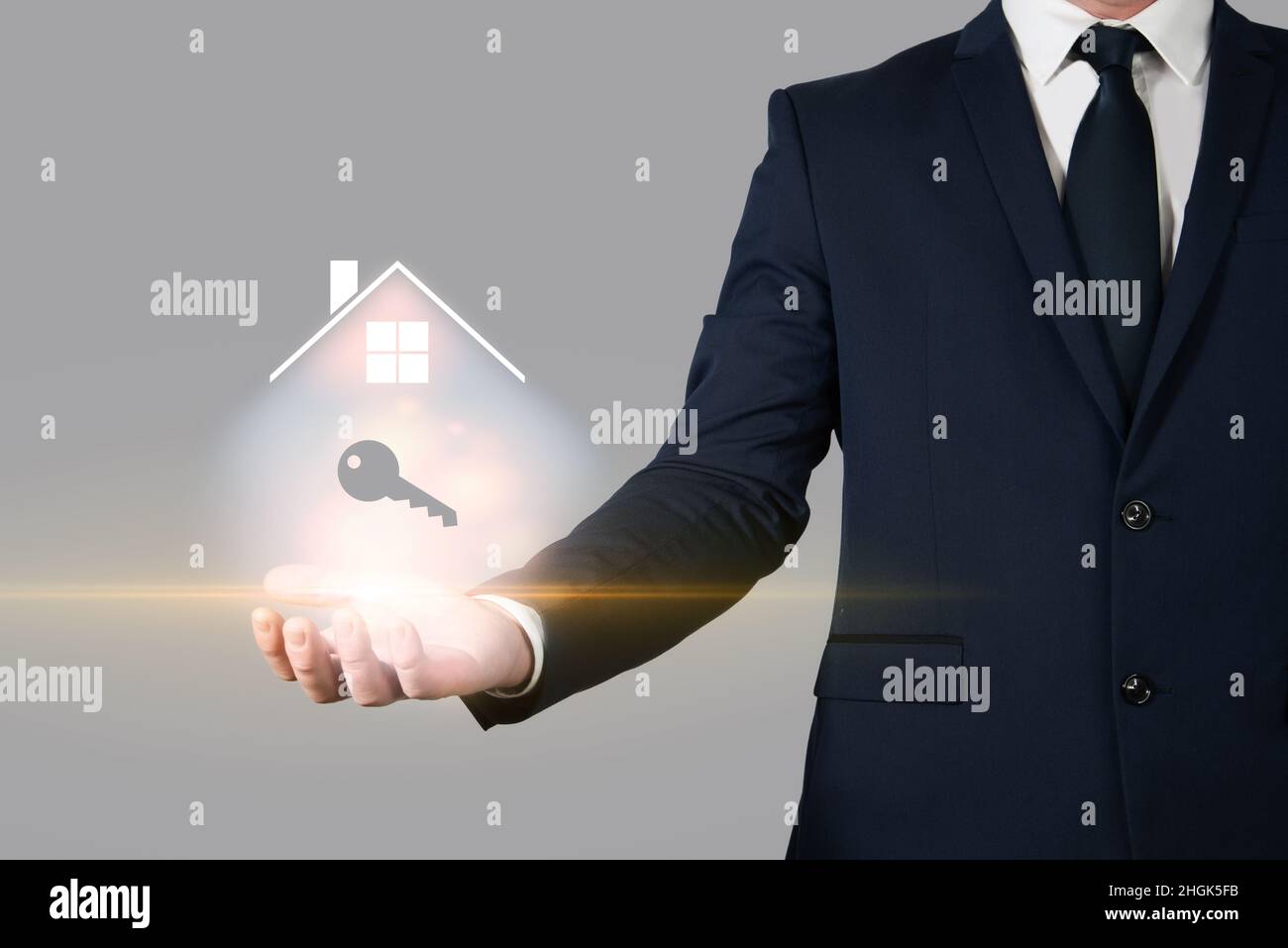 Uomo d'affari che tiene una casa nel palmo della sua mano accanto ad alcune chiavi. Investimento immobiliare e assicurazione casa Foto Stock