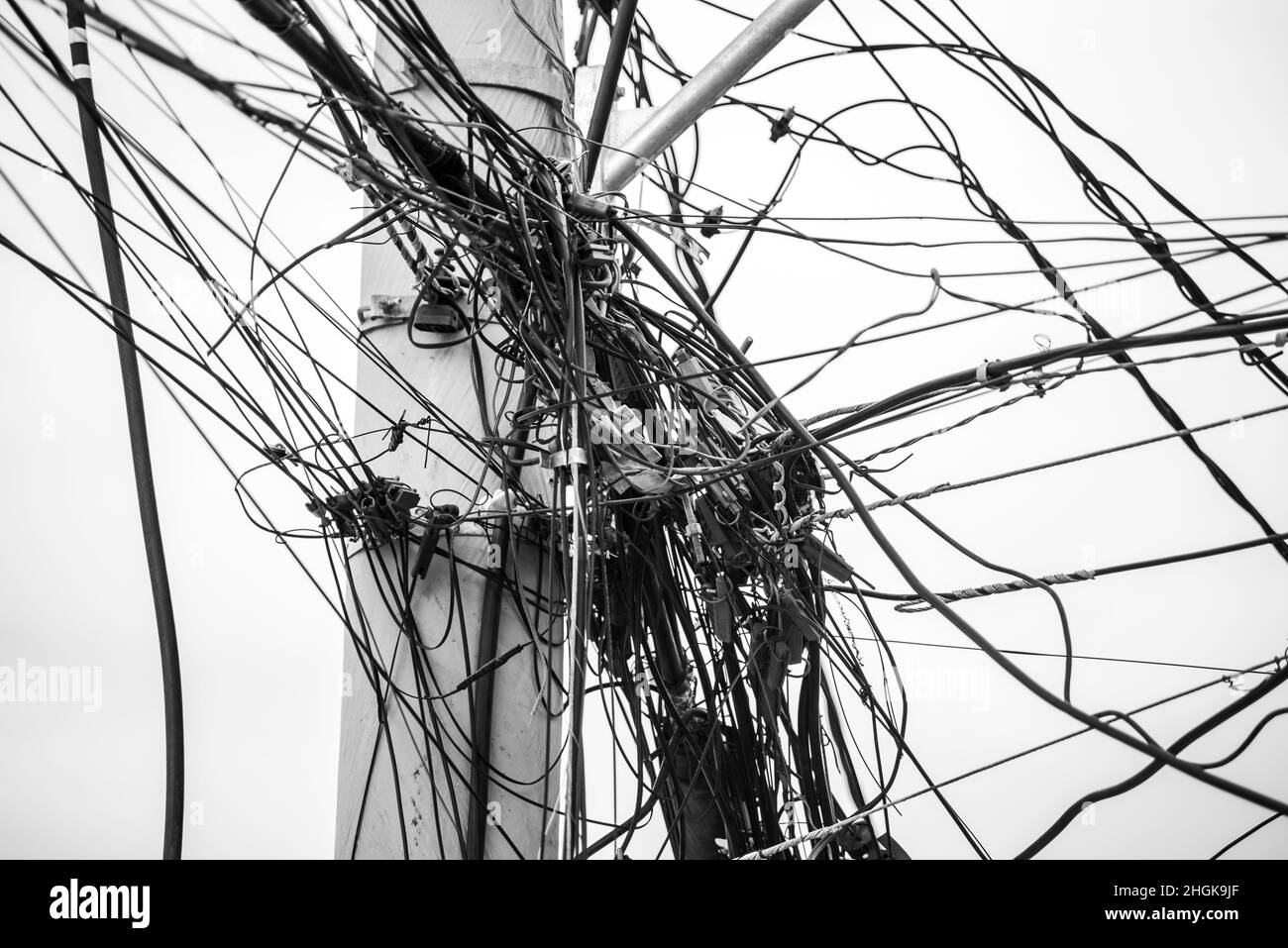 Groviglio di fili e cavi su un palo contro il cielo limpido. Salvador, Bahia, Brasile. Foto Stock