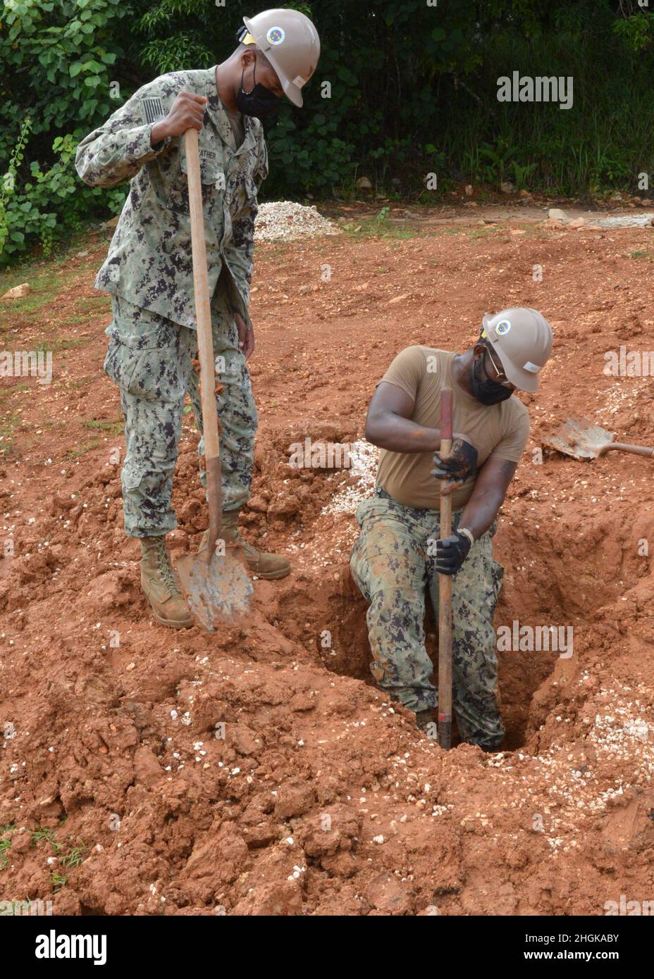 SANTA RITA, Guam (settembre 1, 2021) Edilizia elettricista terza classe Adrian Ppiuttosto e Utilitiesman Constructionman Ladarryl corpo, assegnato a Naval Mobile Construction Battalion (NMCB) 1 distaccamento Guam, scavo al progetto di conversione Outhouse. NMCB 1 distaccamento Guam è stato implementato in avanti per eseguire la costruzione, l'assistenza umanitaria, la cooperazione per la sicurezza del teatro, e sostenere la manovra della flotta nelle aree operative della 7a flotta degli Stati Uniti. Foto Stock