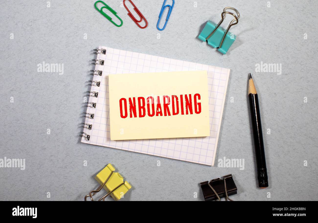 Simbolo di onboarding. Nota bianca con una parola 'onboarding' su bel tavolo di legno, carta colorata, matite colorate, graffette, monete e calcolatrice. B Foto Stock