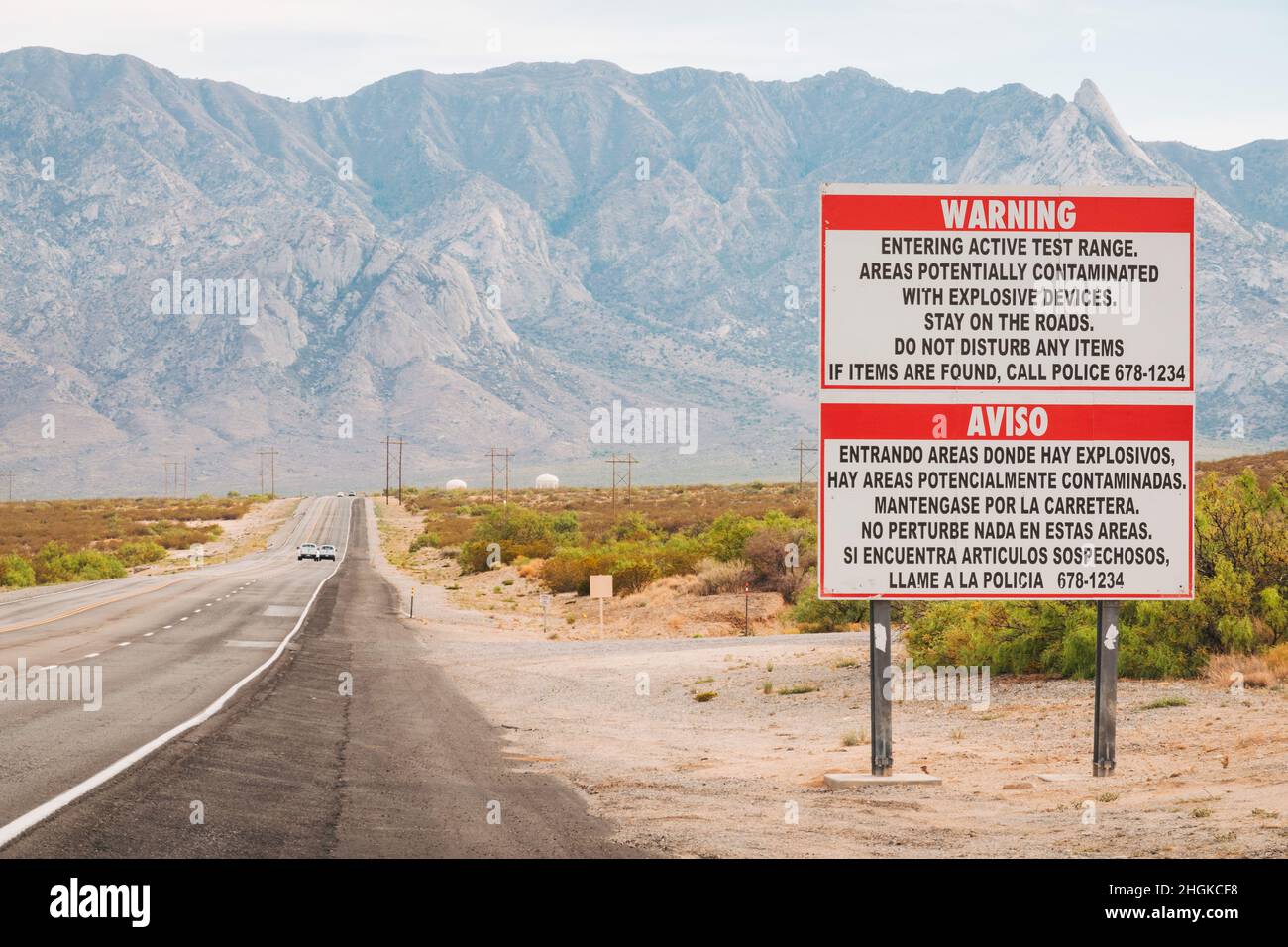 Un cartello avverte in inglese e spagnolo della possibilità di ordinanze inesplose sulla strada d'ingresso alla White Sands Missile Range, New Mexico, USA Foto Stock