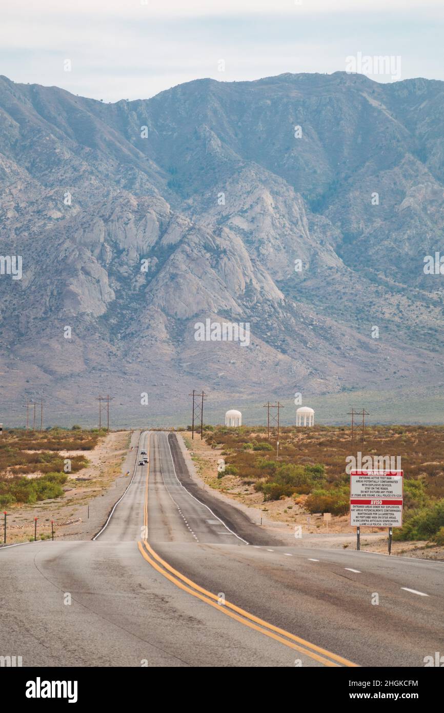 Un cartello avverte in inglese e spagnolo della possibilità di ordinanze inesplose sulla strada d'ingresso alla gamma missilistica di White Sands, New Mexico Foto Stock
