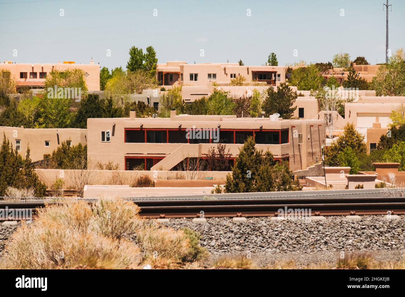 Una pista ferroviaria passa da un sobborgo di Santa Fe, New Mexico, che presenta numerose case costruite in stile adobe Foto Stock