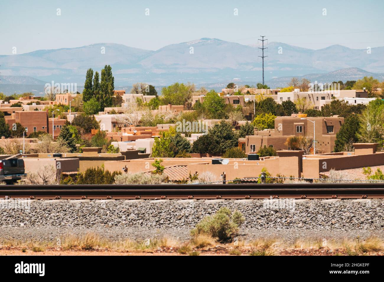 Una pista ferroviaria passa da un sobborgo di Santa Fe, New Mexico, che presenta numerose case costruite in stile adobe Foto Stock