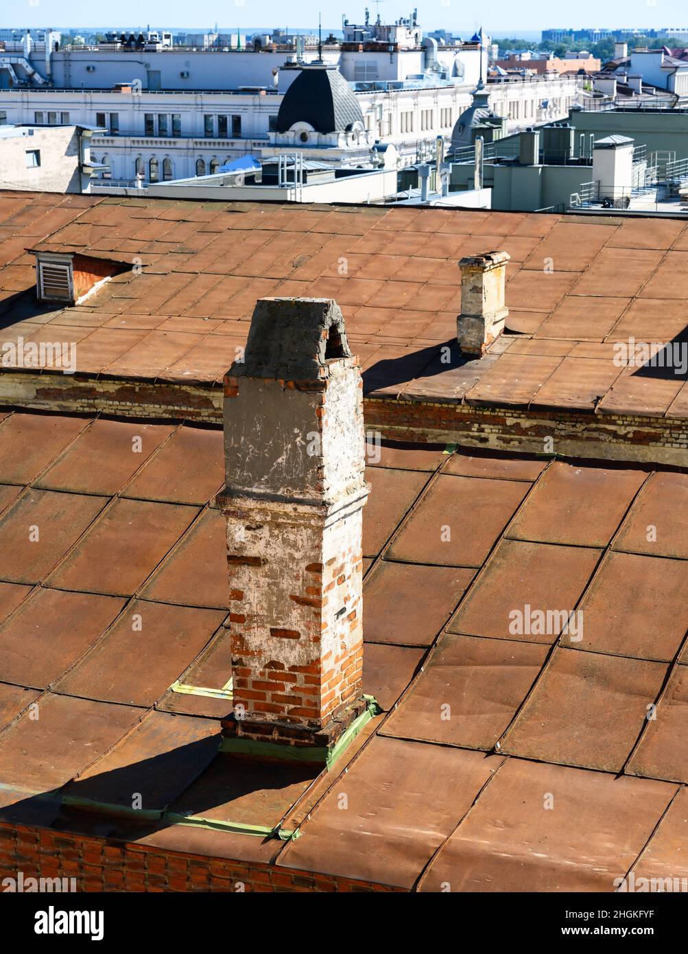 Camino sul tetto dell'edificio urbano. Camino tradizionale rosso mattone primo piano, sistema di ventilazione sulla parte superiore della casa. Vecchi tubi camino sullo sfondo del tetto me Foto Stock