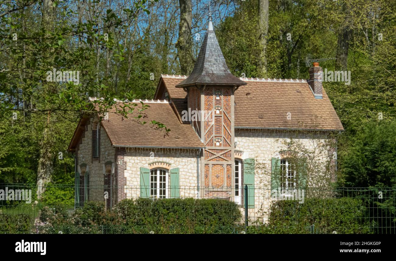 Pittoresca vecchia casa francese con persiane verde chiaro e una torre annidata nel bosco Foto Stock