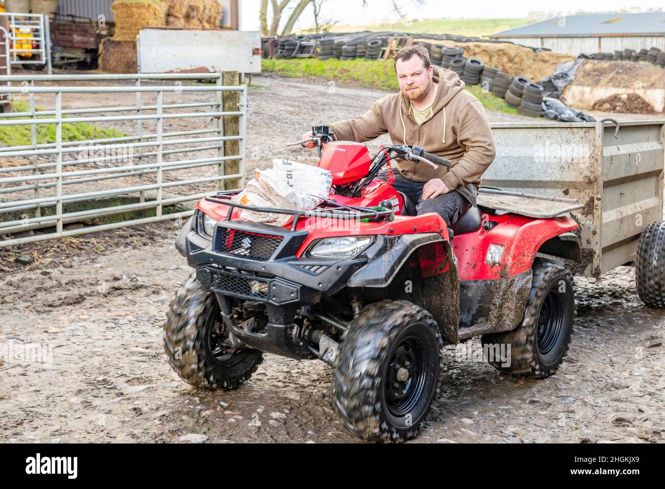 Giovane agricoltore maschio che guida quad rosso in fattoria Matfen Northumberland Foto Stock
