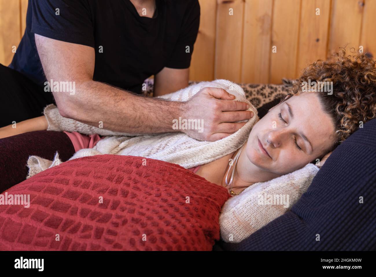Una donna caucasica rilassata è vista sdraiata sul suo lato con gli occhi chiusi mentre medita durante un trattamento Shiatsu tradizionale con spazio copia. Foto Stock