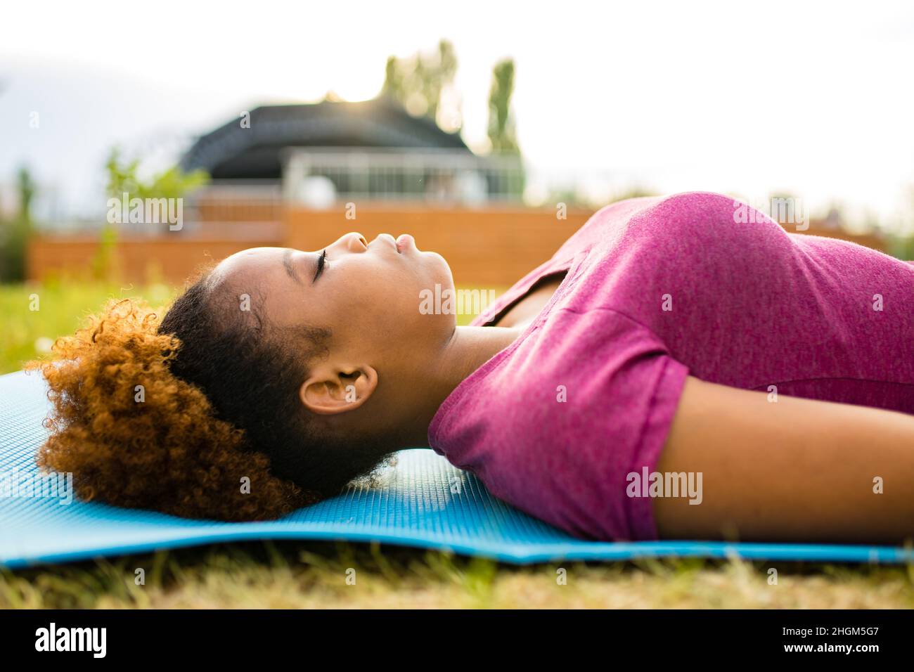 Giovane allenatore afro-americano felice con capelli ricci corti pronti per il tempo di yoga all'aperto Foto Stock