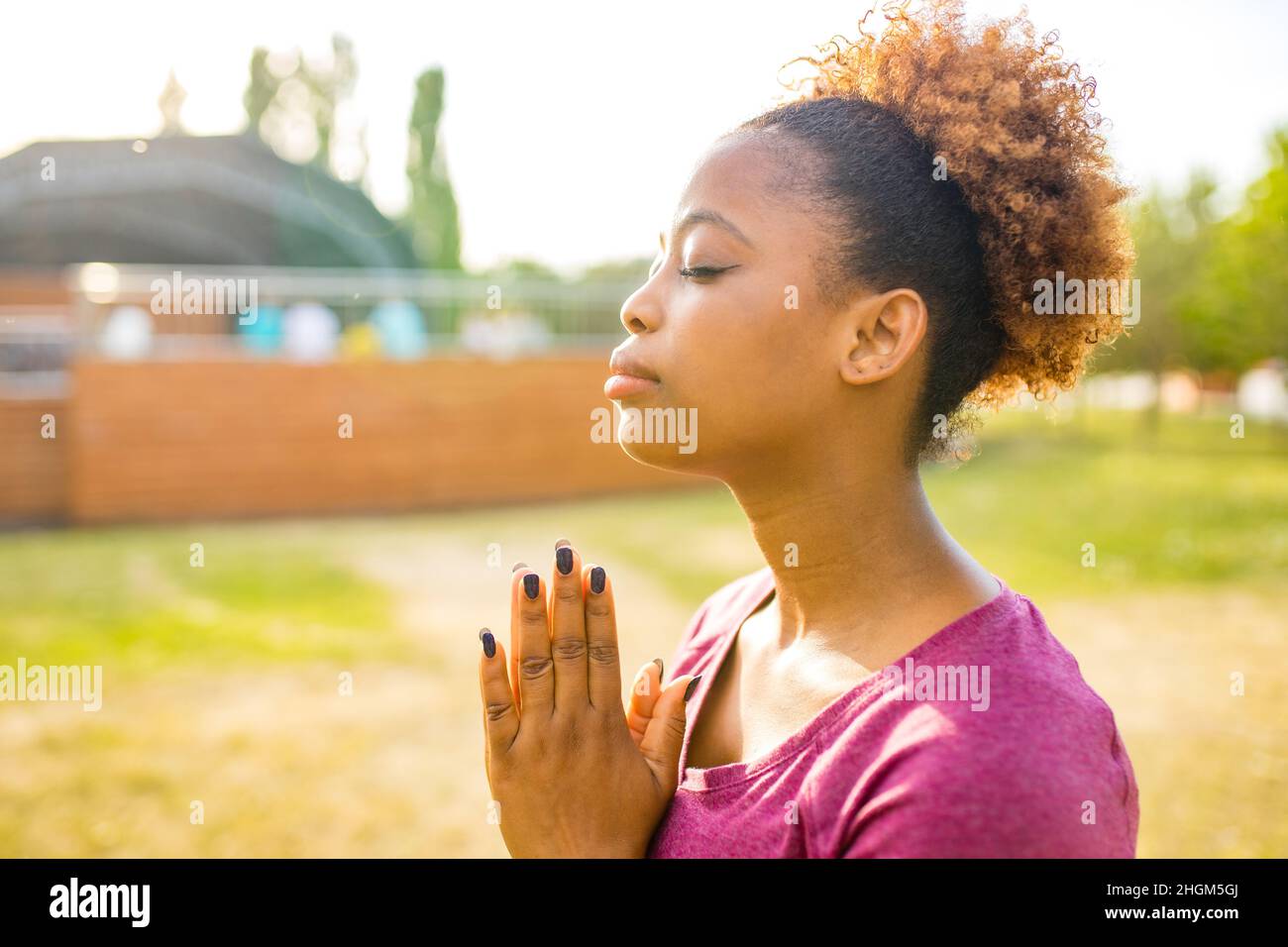 Giovane allenatore afro-americano felice con capelli ricci corti pronti per il tempo di yoga all'aperto Foto Stock