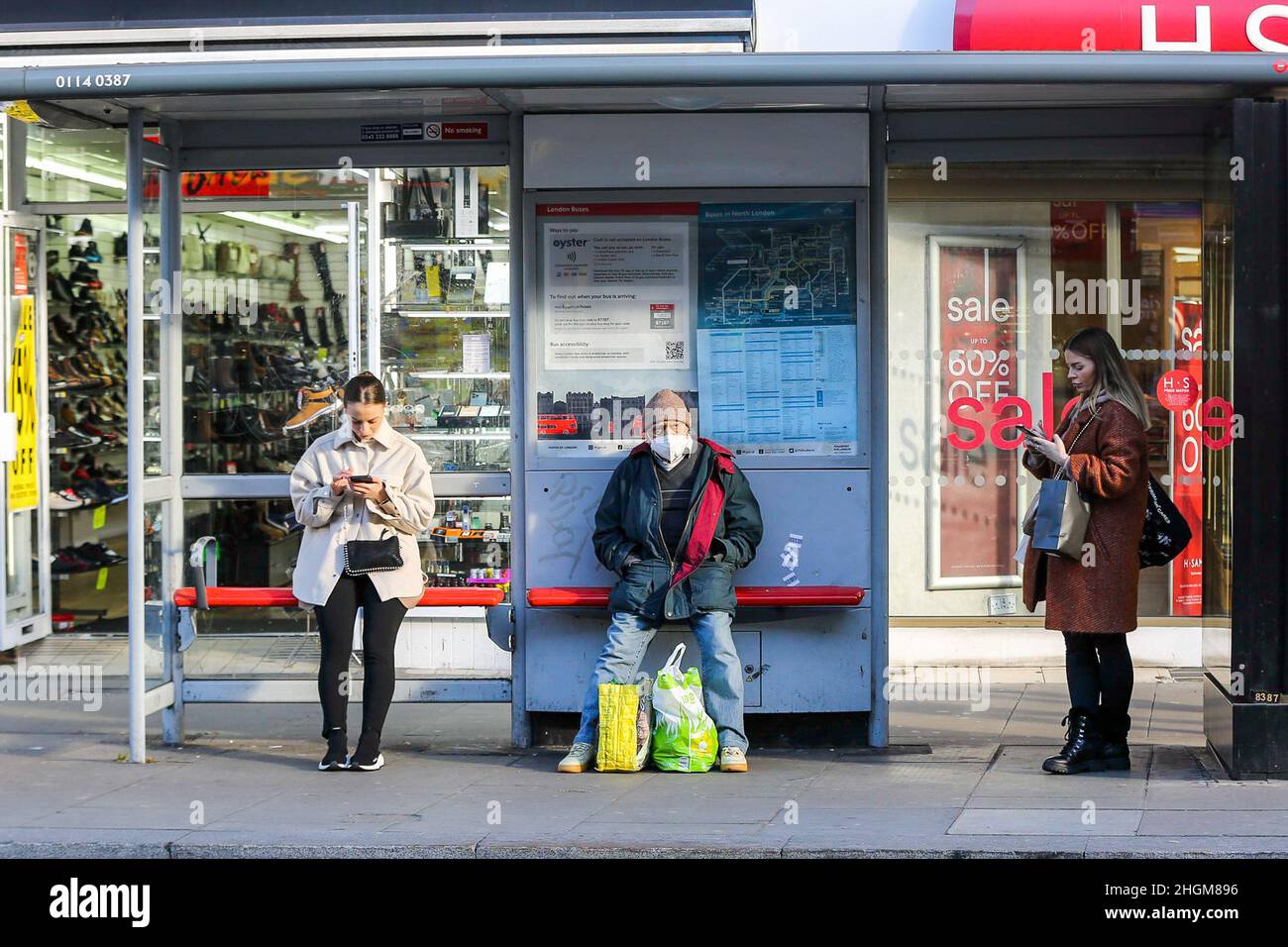 Londra, Regno Unito. 19th Jan 2022. Le donne in attesa di una fermata dell'autobus guardando i loro telefoni cellulari. (Credit Image: © Dinendra Haria/SOPA Images via ZUMA Press Wire) Foto Stock