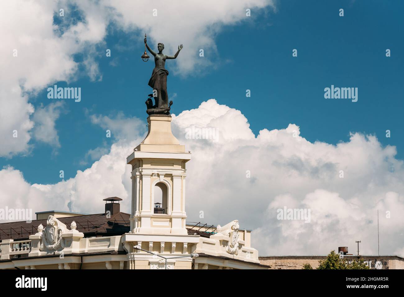 Vilnius, Lituania. Statua di una donna con una Lanterna nelle sue mani sul tetto del Museo dell'energia e della tecnologia contro Un cielo blu soleggiato Foto Stock