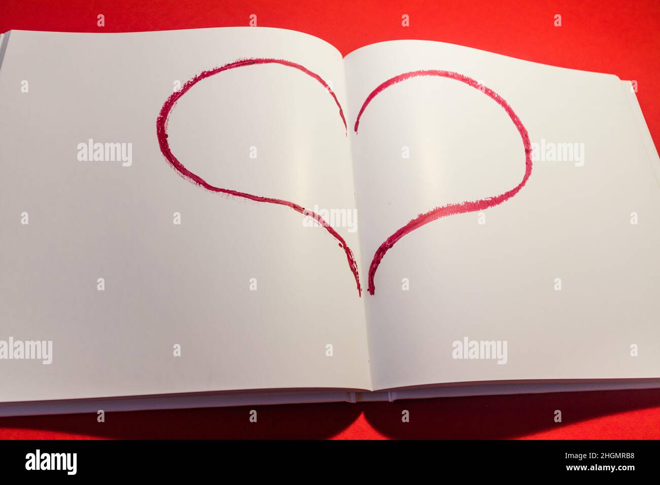 Disegnò il cuore in un notebook su sfondo rosso. Buon San Valentino. Foto Stock