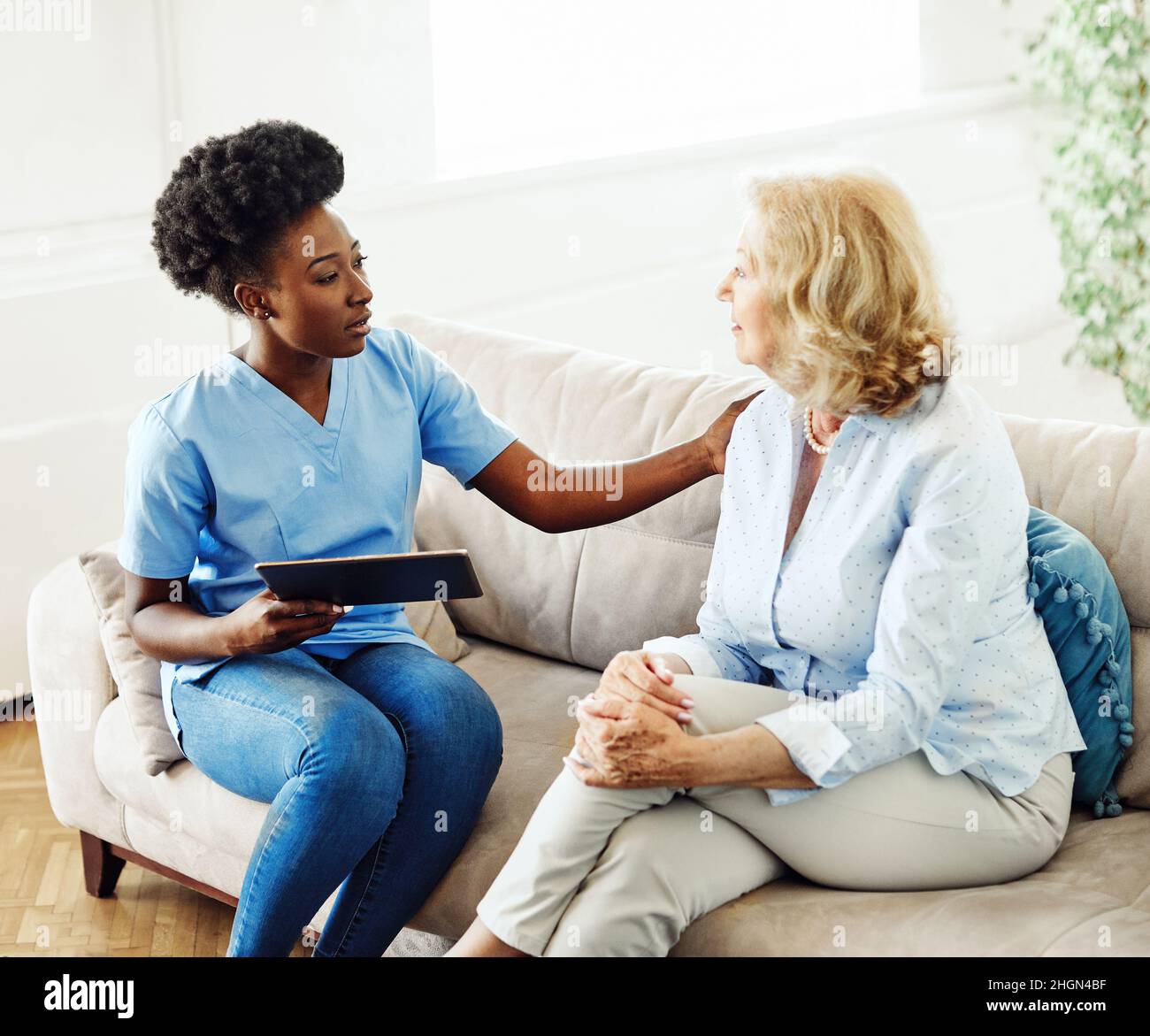 infermiera medico assistenza anziana operatore sanitario aiutare tablet tecnologia pensione casa infermieristica anziana donna salute supporto africano americano nero Foto Stock