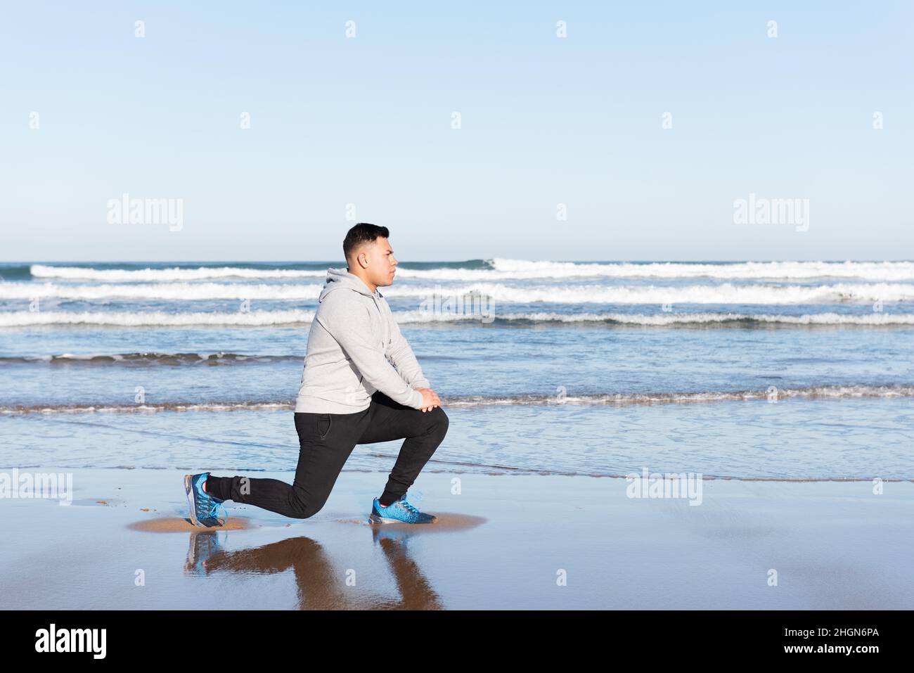 L'uomo latino stretching psoas muscolo al mare Foto Stock