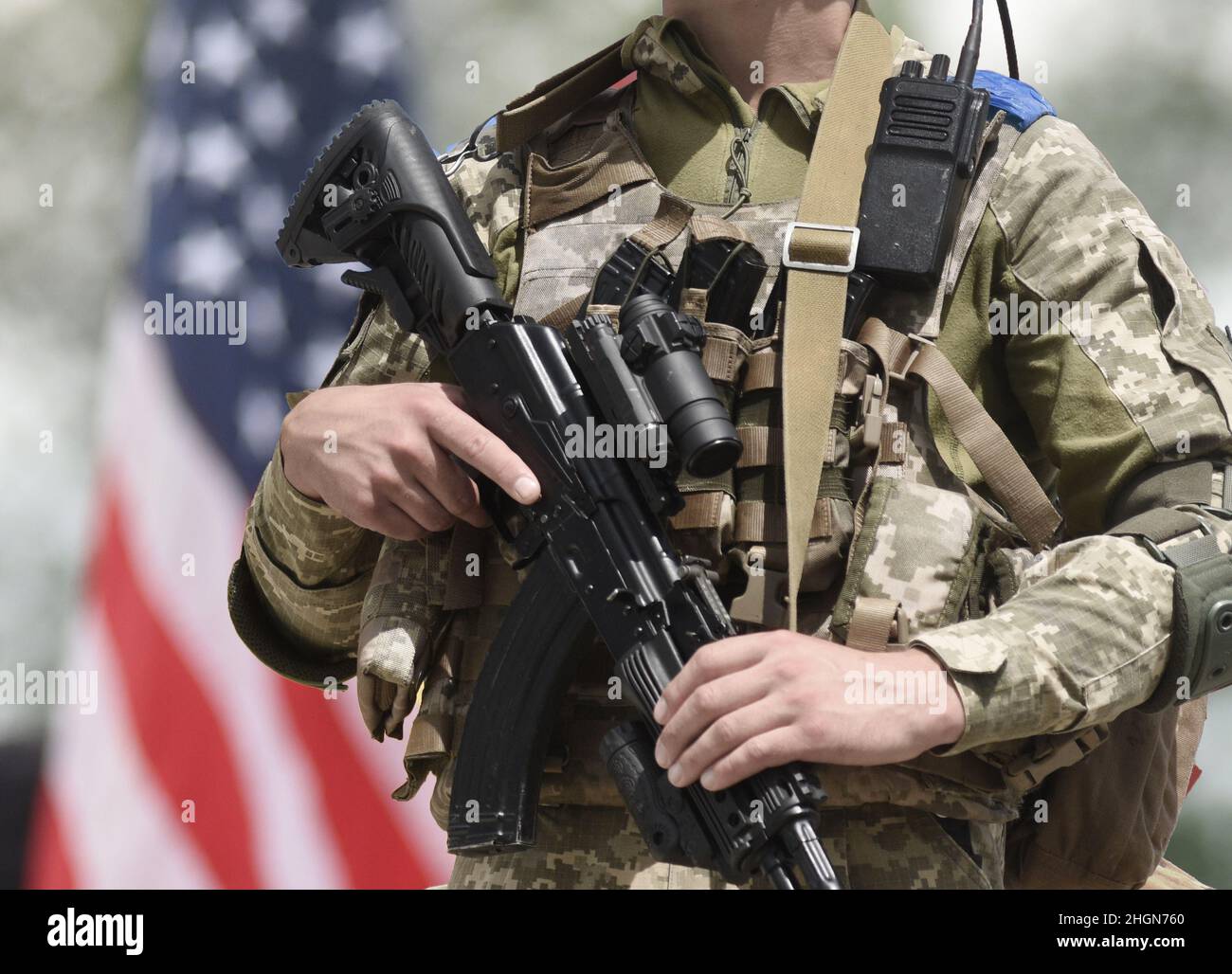 Soldato con fucile d'assalto e bandiera degli Stati Uniti sullo sfondo. Sostegno militare USA Ucraina. Foto Stock