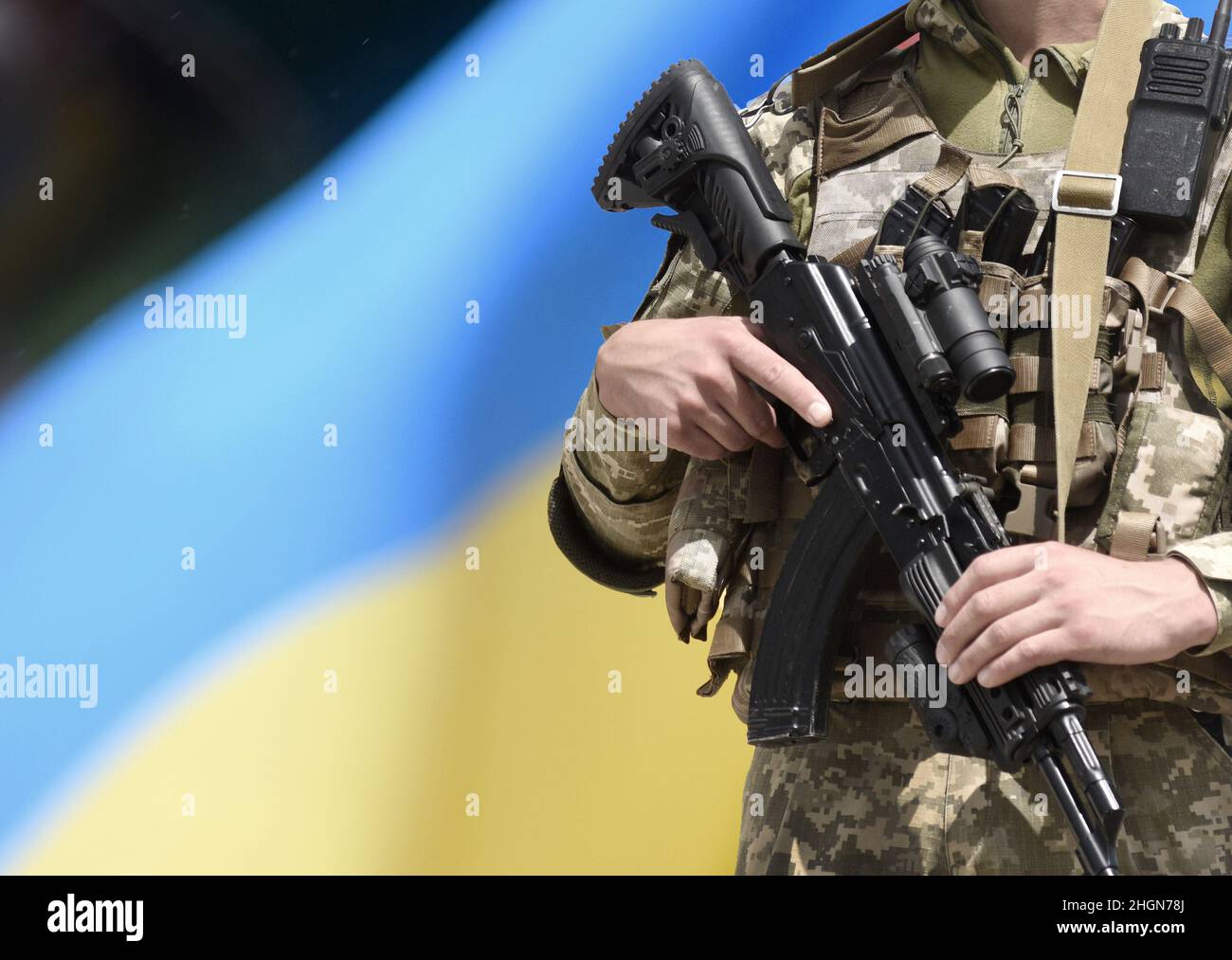 Soldato con fucile d'assalto e bandiera dell'Ucraina. Soldato ucraino con fucile d'assalto AK. Foto Stock