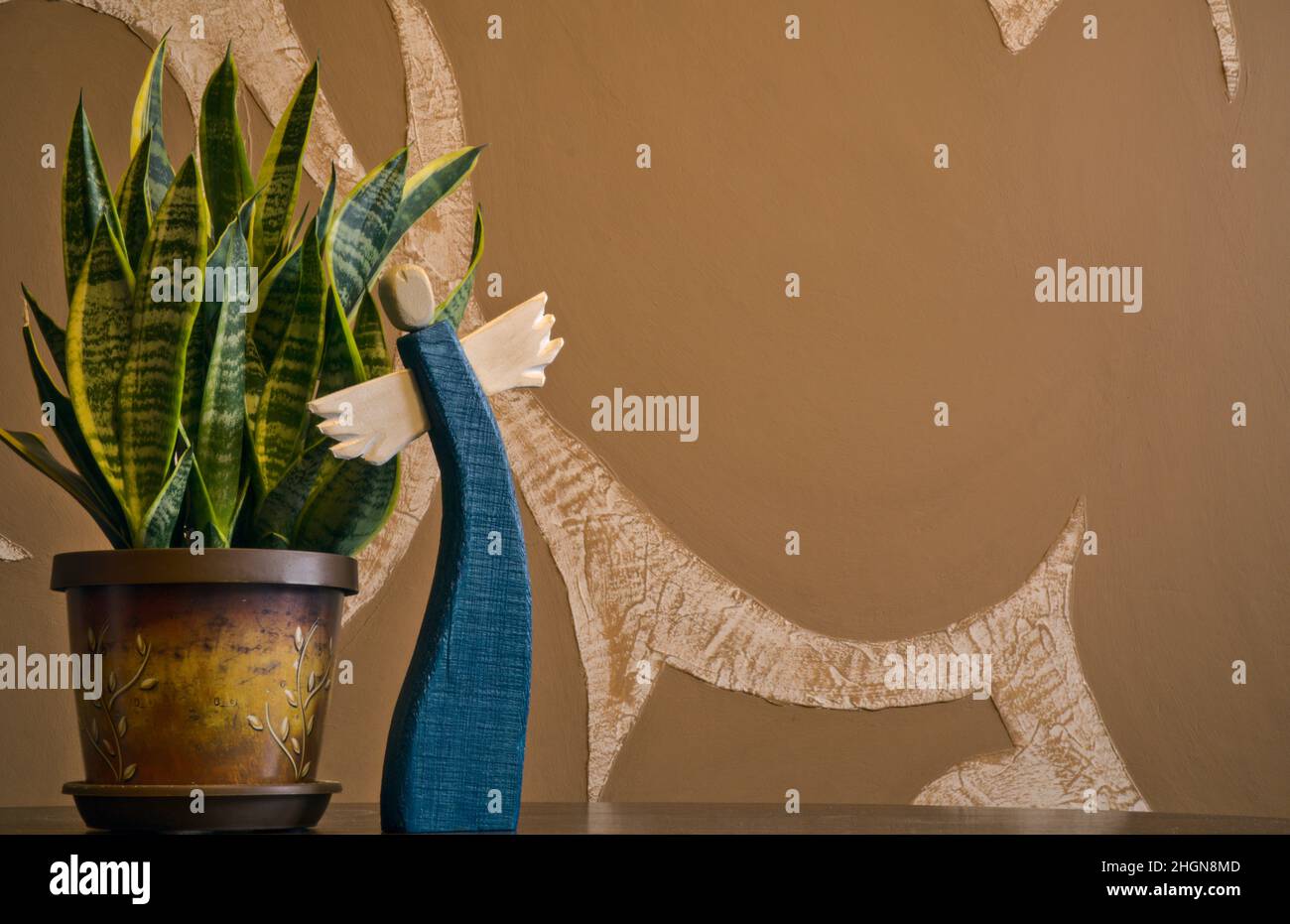 angelo dipinto in legno con pianta verde su sfondo astratto sfocato Foto Stock