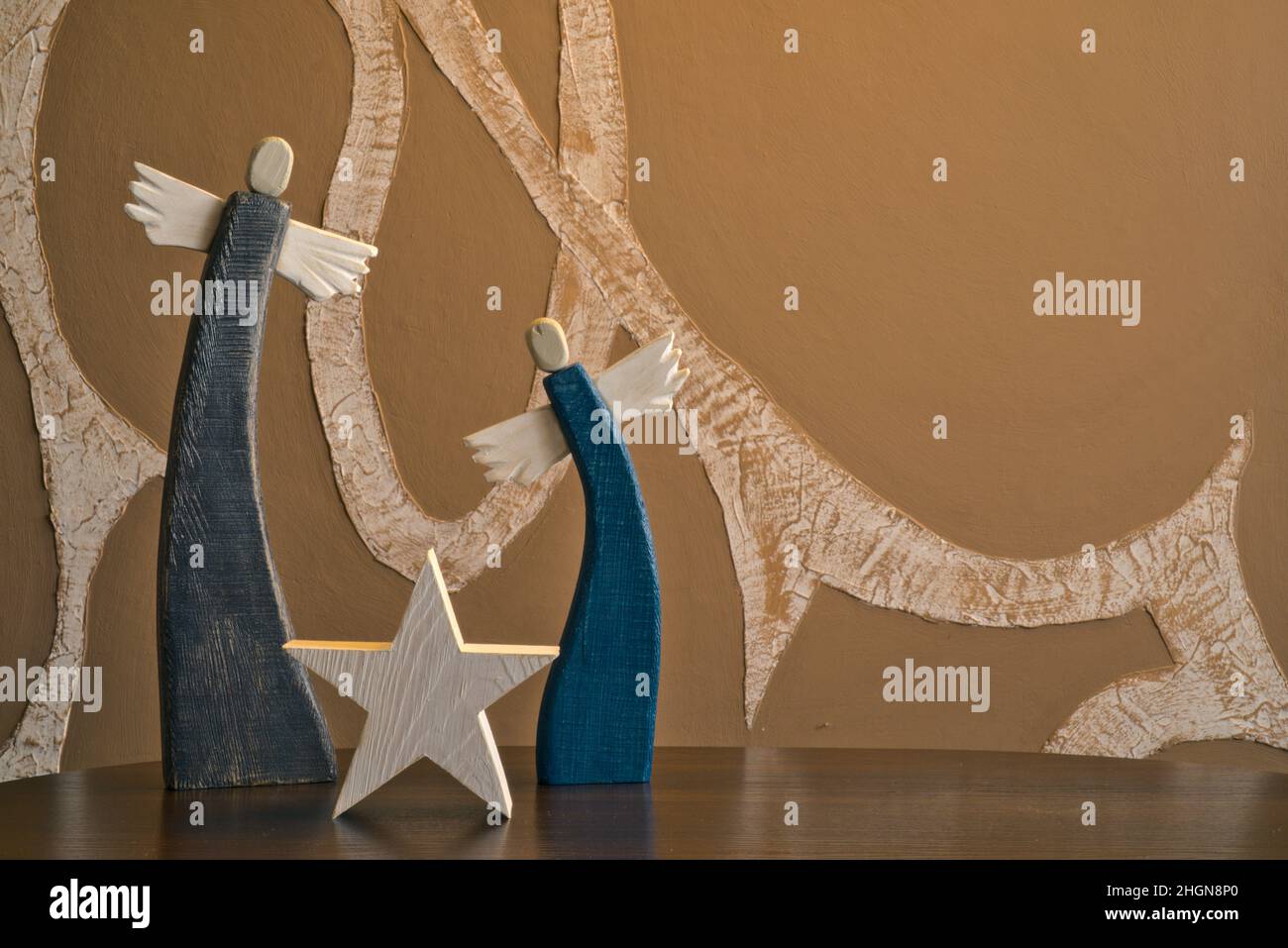 angeli dipinti in legno con stella su sfondo astratto sfocato con motivo tortuoso Foto Stock