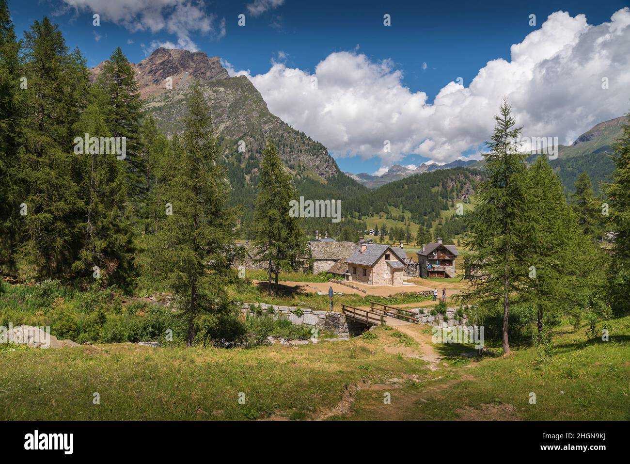 Tipica casa in pietra dell'Alpe Devero, in Piemonte, con alberi e montagne sullo sfondo Foto Stock