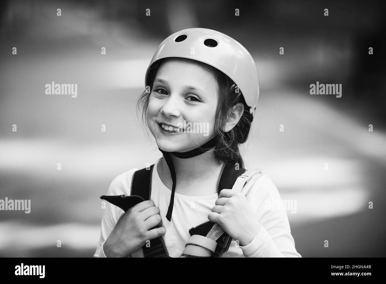 Piccola ragazza che si arrampica nel parco avventura con casco e equipaggiamento di sicurezza. Bambina che sale sul parco a corda alta. Casco e attrezzatura di sicurezza. Foto Stock