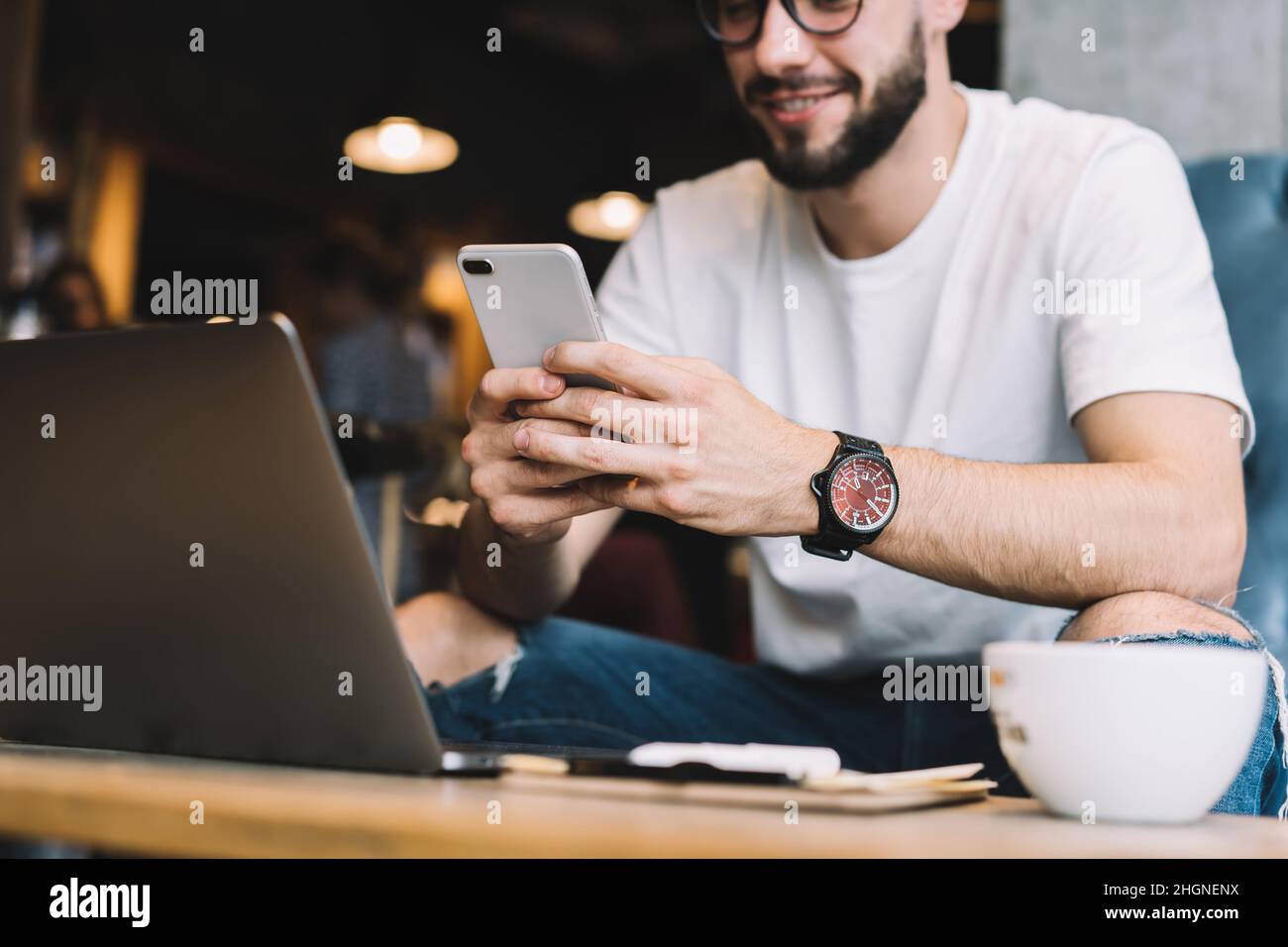Immagine ritagliata del programmatore maschile che utilizza la tecnologia cellulare per controllare la notifica di mobilità Foto Stock