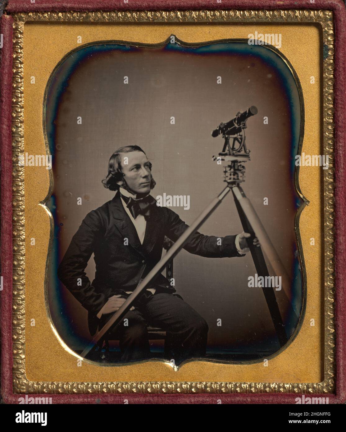 [Surveyor] ca. 1854 Unknown questo ritratto di un topografo di uno studio di daguerreotipo sconosciuto è stato fatto durante il periodo di massimo splendore dell'era Daguerreiana negli Stati Uniti, un tempo che coincise con una crescente necessità di dati di indagine e mappe per la costruzione di ferrovie, ponti e strade. Il topografo non identificato, seduto su una sedia, afferra una gamba del treppiede che sostiene il suo transito, un tipo di teodolite o strumento di rilevamento che comprendeva una bussola e un telescopio rotante. La scena accuratamente composta, in cui l'angolo dello sguardo sopraelevato dell'uomo è allineato con il telescopio e da cui è echeggiato Foto Stock
