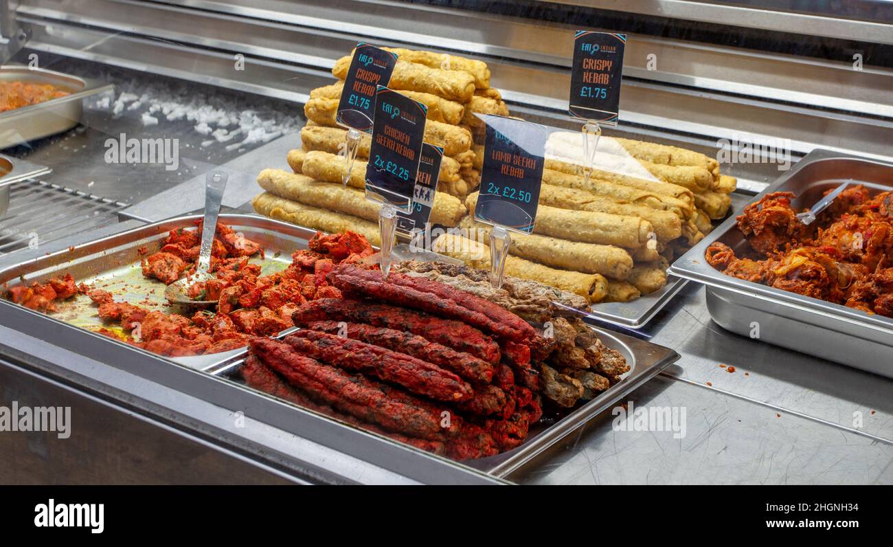 Piatti caldi e piccanti indiani cotti in mostra nel popolare centro città di Preston calore & mangiare take-away. Agnello Seekh Kebab, pollo Seekh Kebab, kebab croccante. Tutto in vendita per i commensali Foto Stock