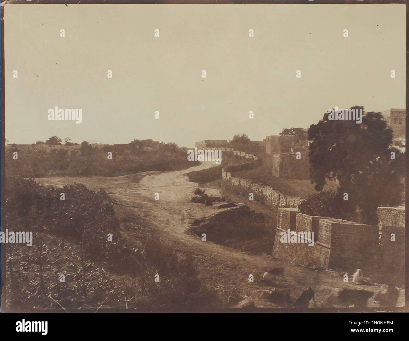 [Mura di Jaffa vicino alla porta di Gerusalemme] 1860 Louis Vignes Vignes, ufficiale navale e fotografo dilettante, ha fatto per la prima volta delle fotografie sulle campagne attraverso la Sicilia, la Turchia e la Terra Santa tra il 1859 e il 1862. Questa vista pittoresca delle mura intorno a Jaffa originariamente formava la parte sinistra di un trittico panoramico della città portuale vista dalla strada per Gerusalemme. Le mura, costruite durante la ricostruzione di Jaffa dopo l'assedio di Napoleone nel 1799, furono demolite nel 1870 per consentire l'espansione della città. [Mura di Giaffa vicino alla porta di Gerusalemme]. Louis Vignes (francese, 1831–18 Foto Stock