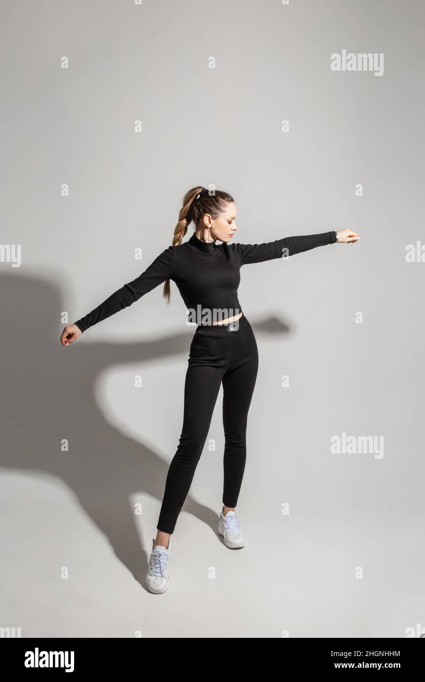 Giovane ragazza elegante che indossa un abbigliamento sportivo nero su  sfondo grigio dello studio con spazio copia. Ad mock in su per deposito di  vestiti Foto stock - Alamy