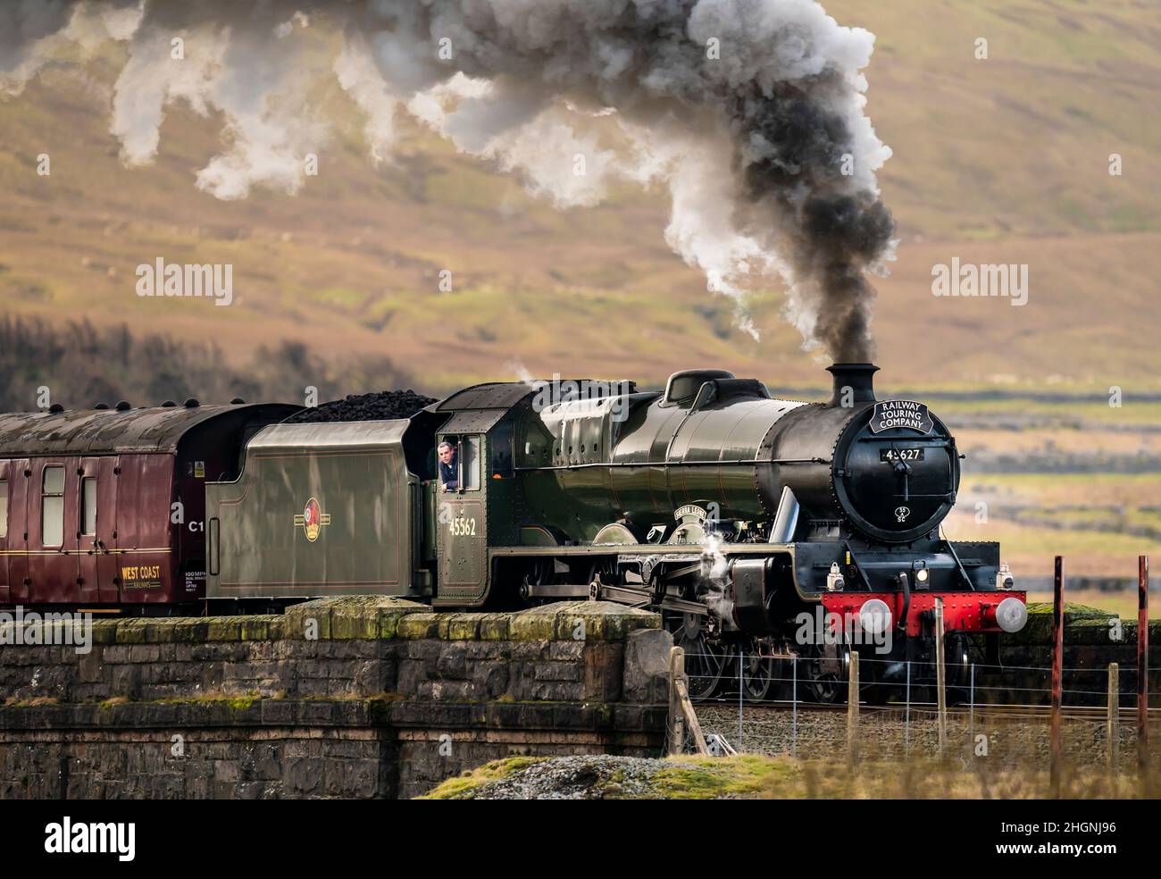 Una persona si affaccia fuori dalla vedova del Winter Cumbrian Mountain Express, la prima linea principale della società treno trainato a vapore del 2022, attraversa Ribblehead Viaduct nel Parco Nazionale Yorkshire Dales. Data foto: Sabato 22 gennaio 2022. Foto Stock